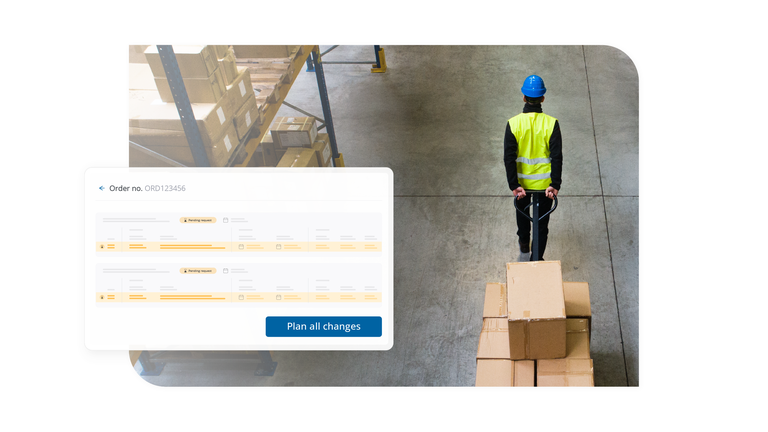 Warehouse worker moving boxes near a dock schedule screen showing order changes