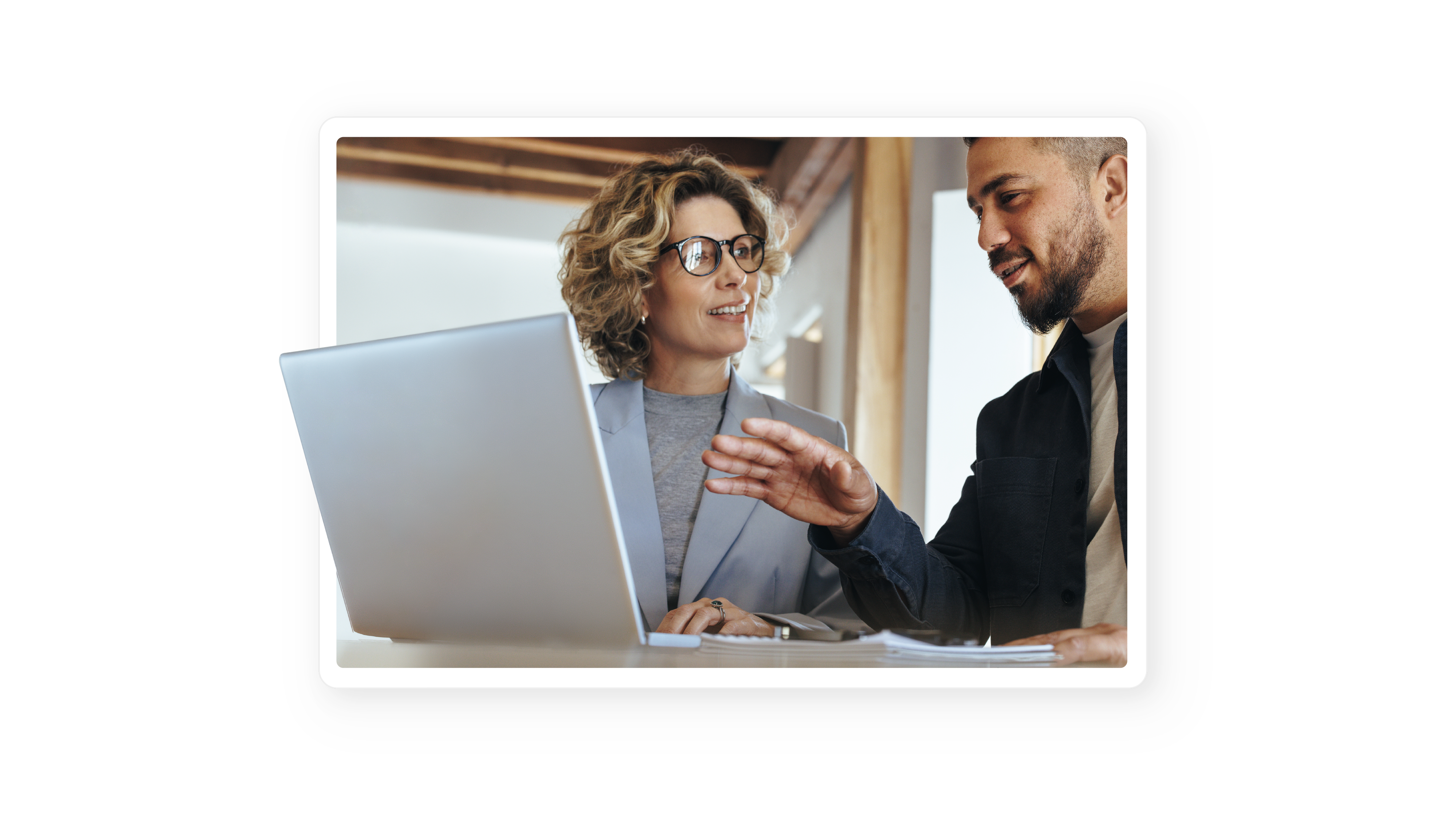 Ein hochwertiges Foto von zwei Fachleuten in einer Büroumgebung, die gemeinsam an Daten arbeiten, die auf einem Laptop-Bildschirm angezeigt werden.