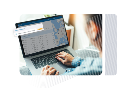 Over-the-shoulder view of a person using a laptop to access the Trimble platform, featuring a map of Europe and an AI-powered search tool.
